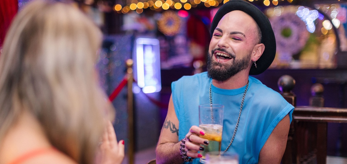 A person chatting and laughing with a friend in a bar