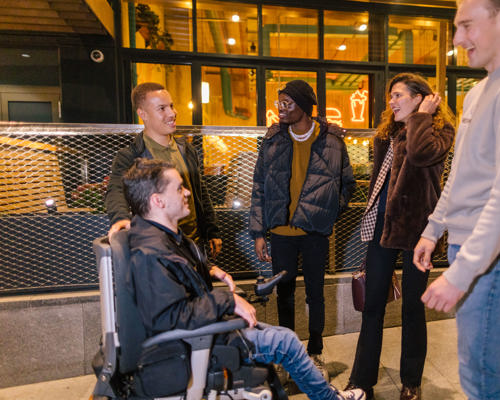 A group of young adults talking and socialising outside a venue