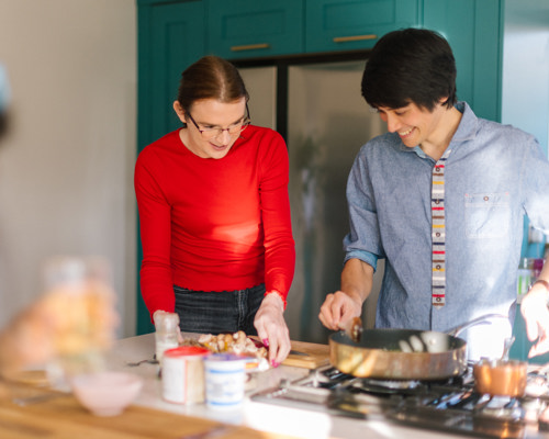 Two housemates dishing up some food from the stove