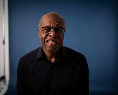 A smiling older black man looking at the camera lens